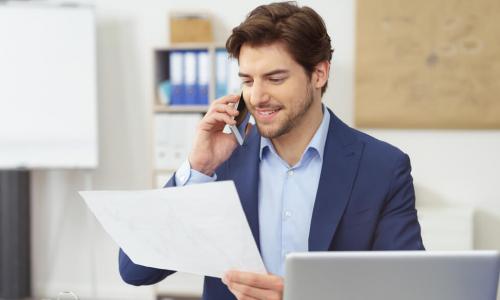 businessman talking on the phone about documents he holds