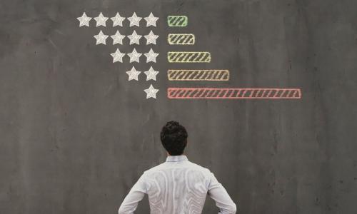 man looking at chalkboard with chart of star ratings