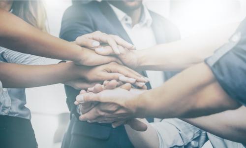 businesspeople stacking their hands together to show team unity and trust