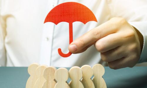 executive holding red paper umbrella over people blocks representing his team