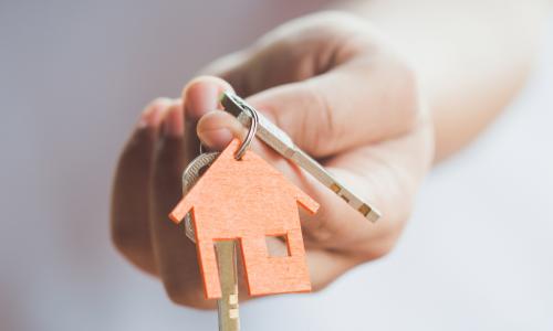 wooden house on key ring held by a hand